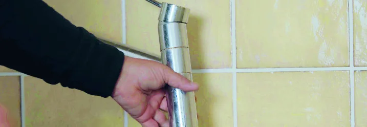 Person hält Wasserhahn über Spüle